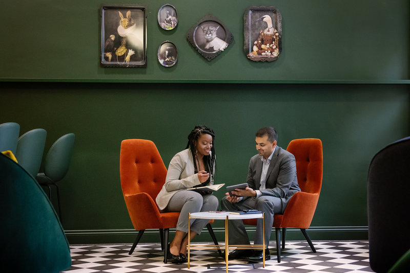 Ajay and LaToya from Sapna Sachania sitting at a coffee table . Ajay is showing LaToya something on an iPad